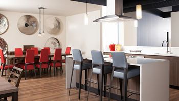 A modern kitchen with red chairs and a wooden table at Skye at Belltown Apartments, Washington 98121